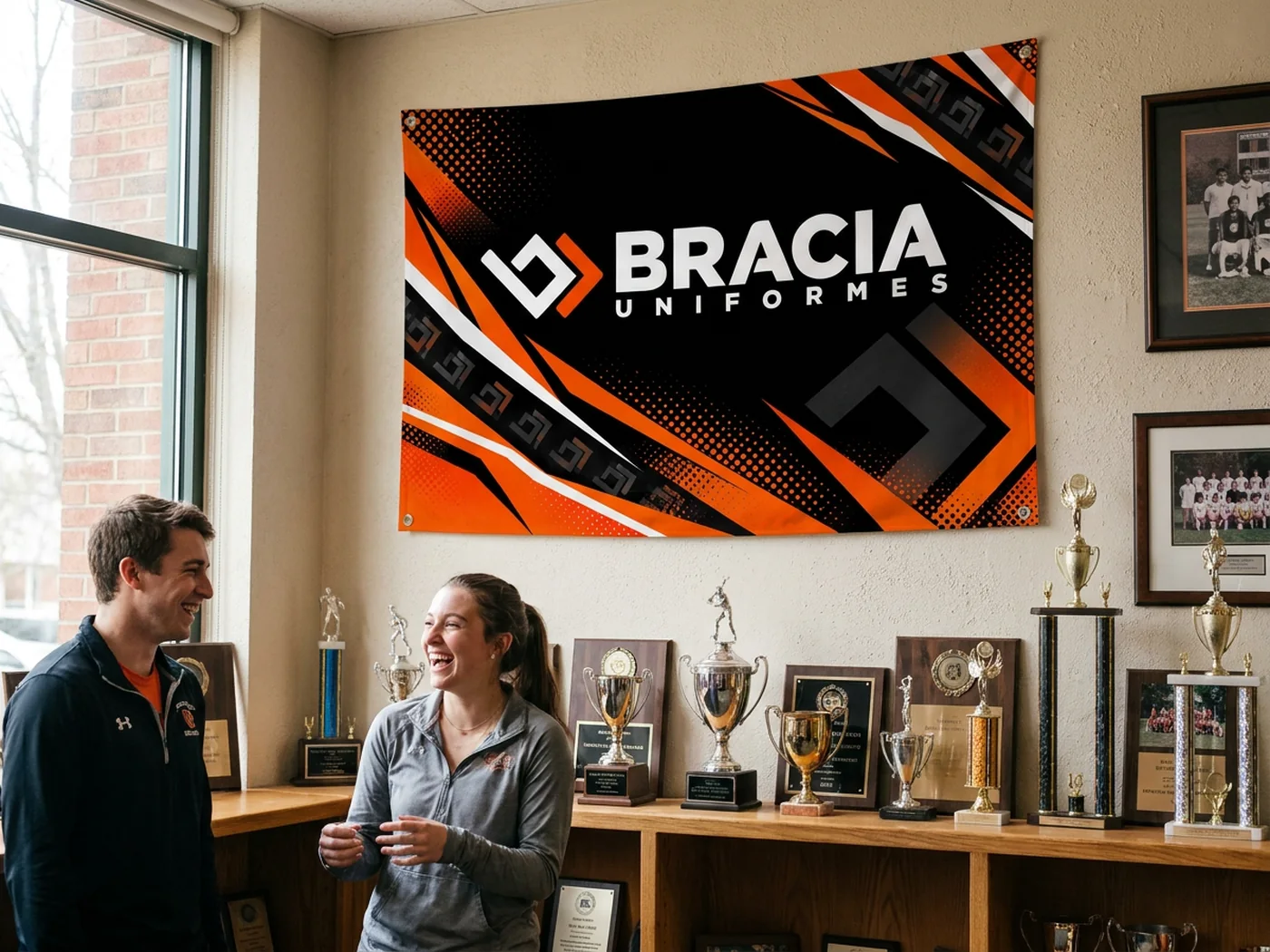Bandeira da Bracia pendurada na parede da sede de uma atlética, com troféus e estudantes conversando